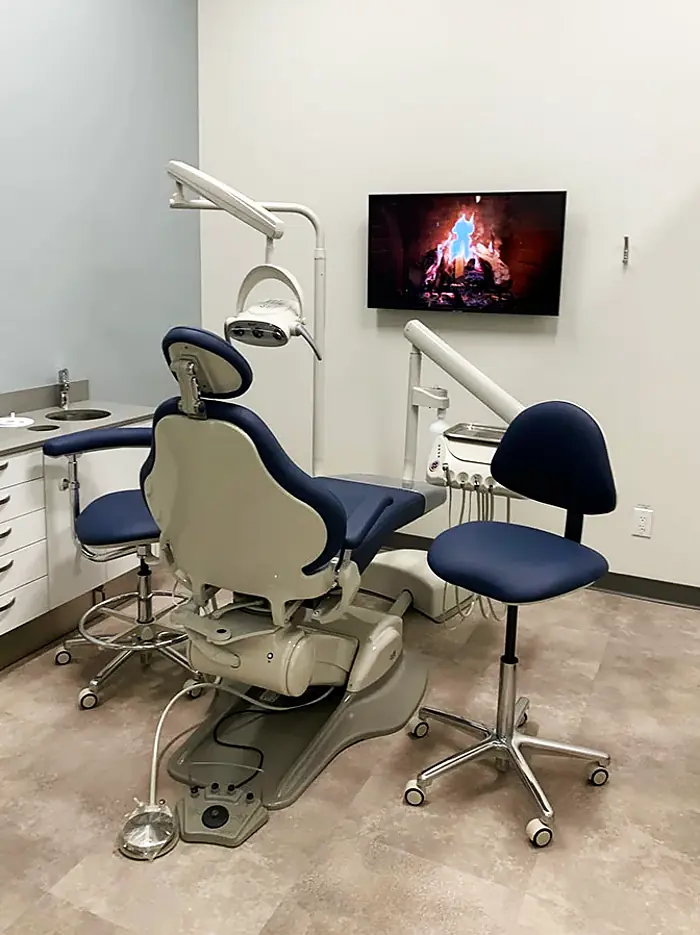Dental operatory at Allard Station Dental with a navy treatment chair and relaxing fireplace screen